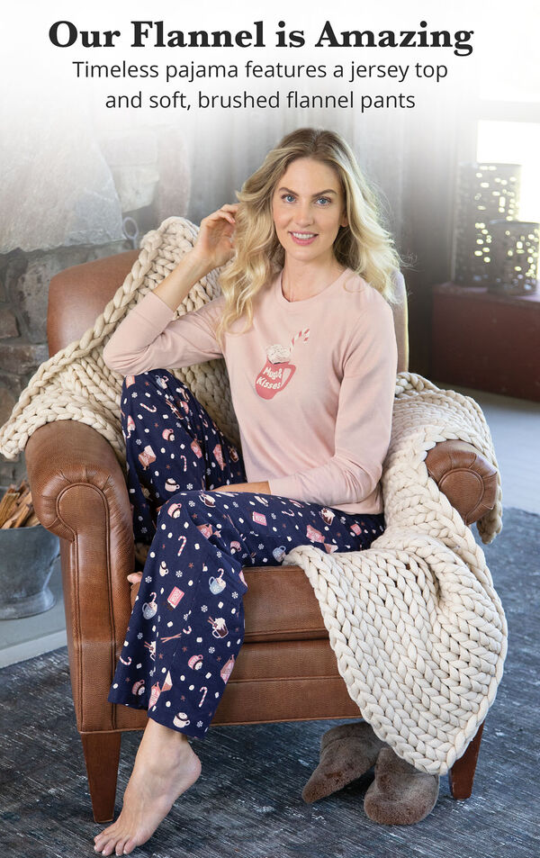 Model sitting on armchair wearing Pink and Navy Blue Mugs & Kisses Pajamas with the following copy: Our Flannel is Amazing - Timeless pajamas features a jersey top and soft, brushed flannel pants