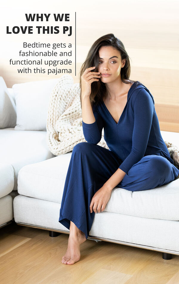 Model sitting on couch wearing Navy Blue Jumpsuit PJs with the following copy: Bedtime gets a fashionable and functional upgrade with this pajama image number 3