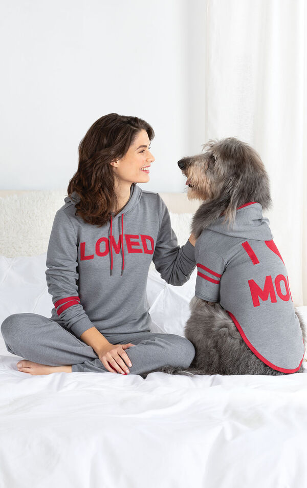 Woman and dog sitting on Bed wearing matching Gray hoodie Pajamas - Woman's says "Loved" on the hoodie and dog's says "I Heart Mom" image number 1