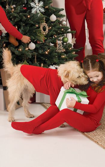 Dog wearing matching Red Thermal PJs by the Christmas Tree