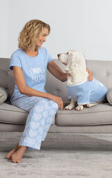 Model wearing Dog Mom PJs sitting on couch petting Dog wearing Fur Baby PJs image number 0