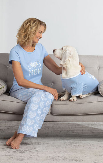 Model wearing Dog Mom PJs sitting on couch petting Dog wearing Fur Baby PJs