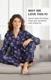 Model sitting on couch wearing Margaritaville Flannel Boyfriend Pajamas - Christmas Palm Trees print with the following copy: Island vibes and holiday cheer pair perfectly with these PJs image number 2