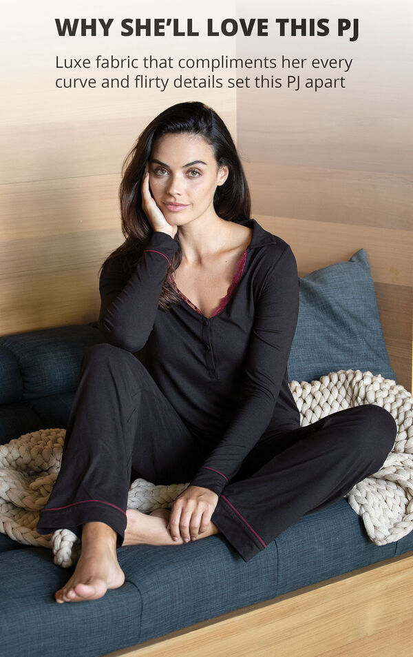 Model sitting on couch wearing Midnight Fantasy Pajamas - Black with the following copy: Luxe fabric that compliments her every curve and flirty details set this PJ apart image number 2