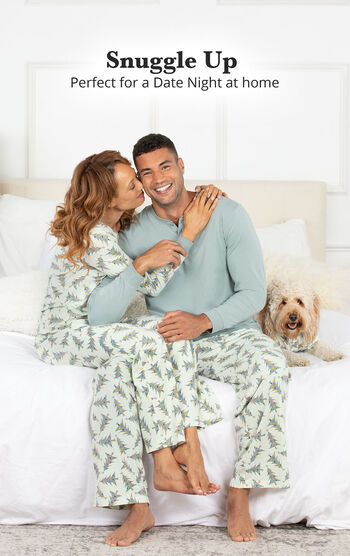 Couple sitting on the couch wearing matching Balsam & Pine Pajamas with the following copy: Snuggle Up - Perfect for a Date Night at Home