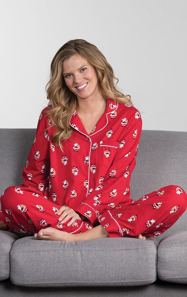 Model sitting cross-legged on couch wearing Red St. Nick Boyfriend Pajamas