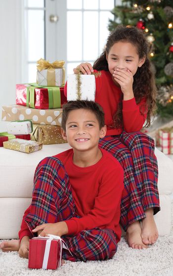 Brother and sister sitting in front of Christmas Tree with presents, wearing matching Classic Red Stewart Plaid Thermal-Top Pajamas