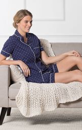 Model sitting on couch with blanket wearing Navy Classic Polka-Dot Short Set image number 2