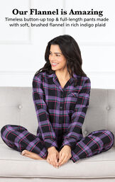 Model sitting on couch wearing Black and Purple Modern Plaid Boyfriend Flannel Pajamas with the following copy: Timeless button-up top and full-length pants made with soft, brushed flannel in rich indigo plaid image number 2