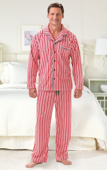 Model standing by bed wearing Red and White Striped Candy Cane Fleece Men's Pajamas 