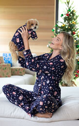Model sitting on bed holding up puppy wearing matching Mugs & Kisses Flannel Boyfriend Pajamas image number 2