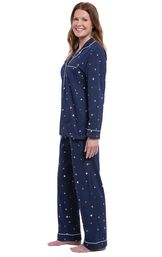 Model facing the side wearing Starry Night Boyfriend Pajamas; Navy blue button up pajamas with yellow and white star allover print image number 2