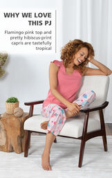 Model wearing Margaritaville Easy Island Capris Pajamas - Pink sitting on chair, with the following copy: Flamingo pink top and pretty hibiscus-print capris are tastefully tropical image number 2
