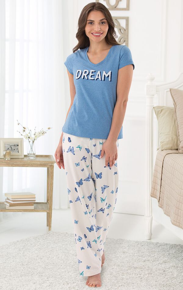 Model standing by bed wearing Blue and White butterfly print Dream Pajamas, facing to the side image number 3