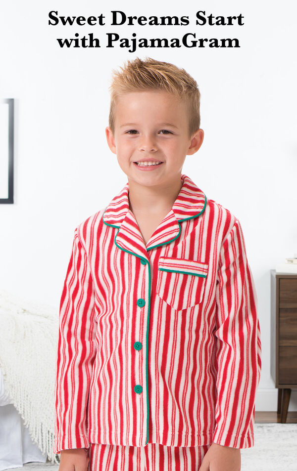 Boy wearing Candy Cane Fleece Boys Pajamas by bed with the following copy: Sweet Dreams Start with PajamaGram. image number 1