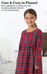 Girl wearing Stewart Plaid Flannel Girls Nighty next to bed with the following copy: Cute and Cozy in Flannel. Girls nightgown is made with soft, brushed polyester flannel in rich Stewart plaid. image number 2