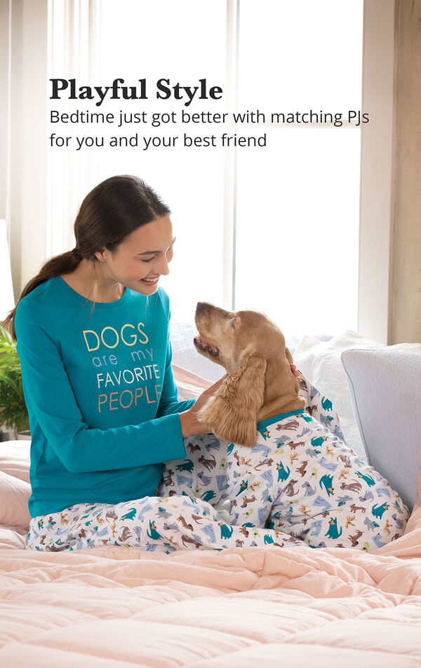 Woman and dog sitting on bed wearing matching Teal and Blue dog print pajamas with the following copy: Playful Style - Bedtime just got better with matching PJs for you and your best friend image number 1
