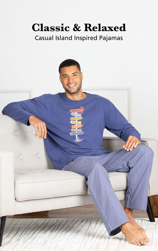 Model sitting on couch wearing Navy Margaritaville Easy Island Men's Pajamas with the following copy: Classic and Relaxed - Casual Island Inspired Pajamas image number 2