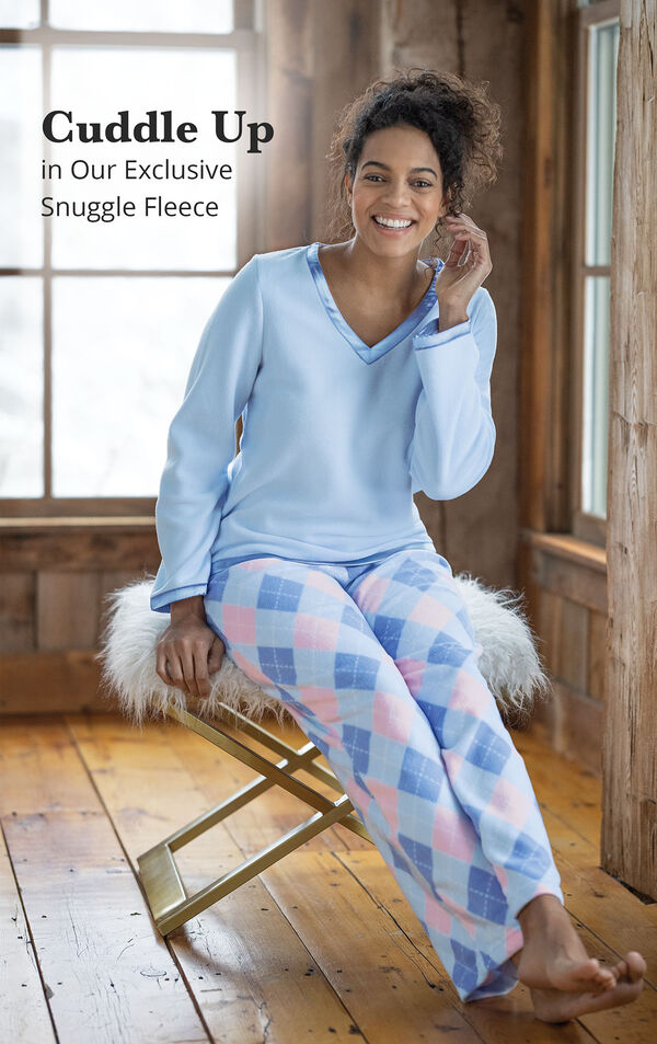 Model wearing Blue and Pink Snuggle Fleece Pajamas - Argyle  sitting with the following copy: Cuddle Up in our Exclusive Snuggle Fleece