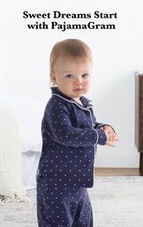 Infant wearing Classic Polka-Dot Infant Pajamas - Navy by bed with the following copy: Sweet Dreams Start with PajamaGram. image number 1