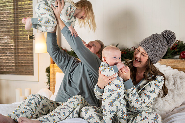 A young family and their children in front of a Christmas tree wearing matching PajamaGram Heritage Plaid pajamas