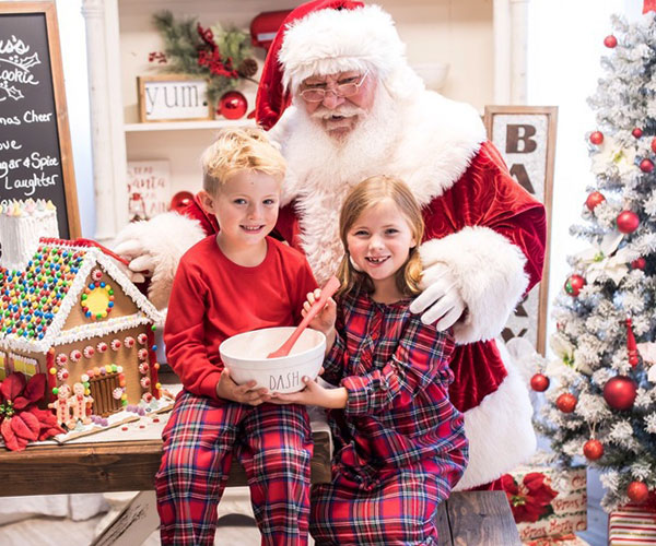 A young boy and girl wearing Stewart Plaid matching pajamas and psing with Santa Claus