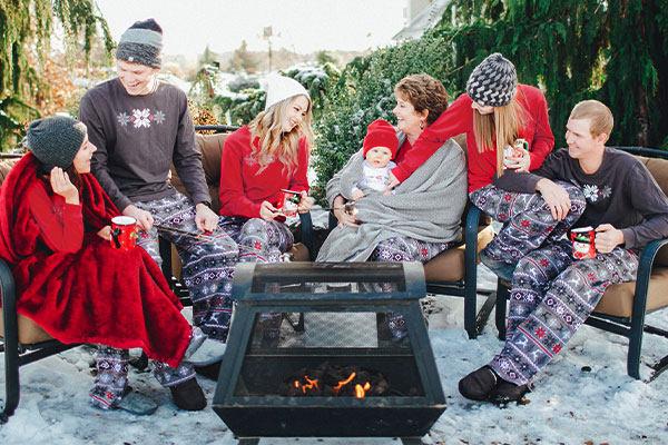 A family sitting around a fire pit wearing PajamaGram Nordic matching family pajamas
