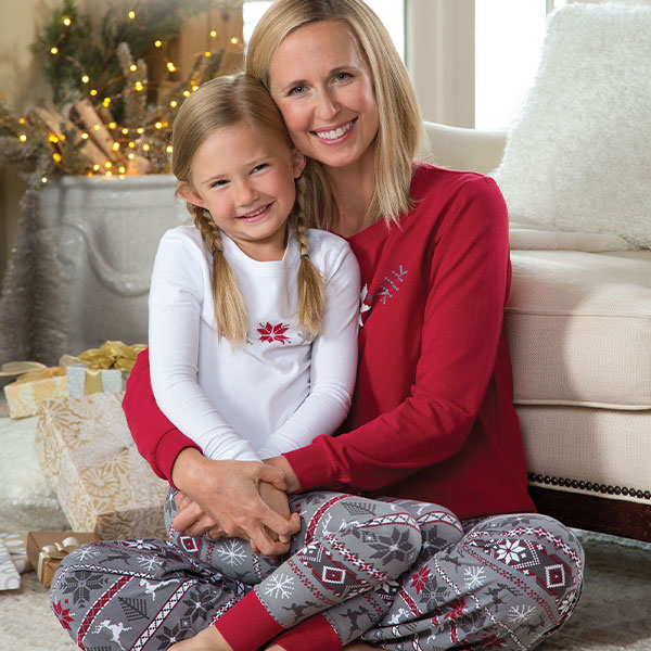A model and a young girl sitting near a couch wearing pajamaGram Nordic matching family pajamas