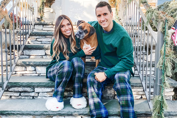 A young couple and a dog wearing matching Heritage Plaid pajamas