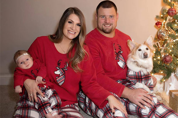 A young famliy and their dog in front of a Christmas tree, all wearing matching Fireside Plaid Fleece pajamas