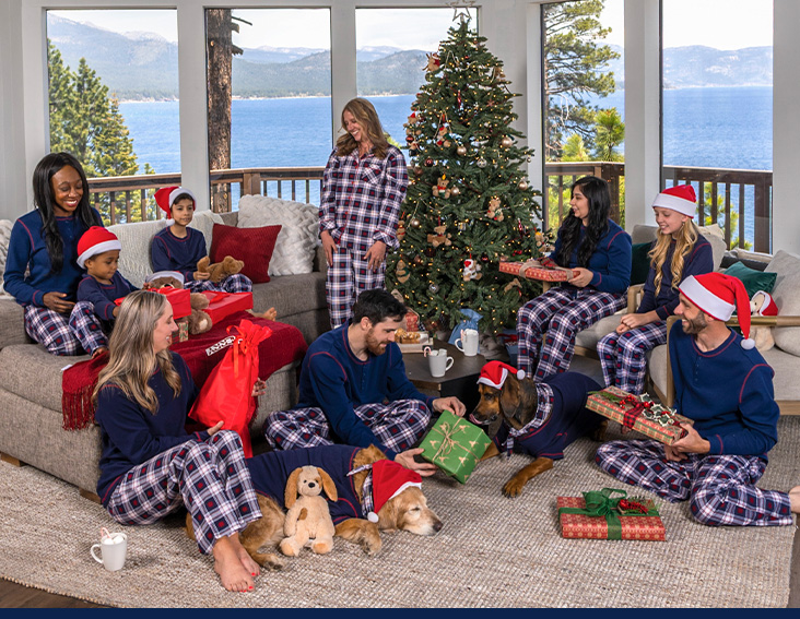 A family celebrating Christmas around the Christmas tree wearing PajamaGram Snowfall Plaid Matching Family Pajamas
