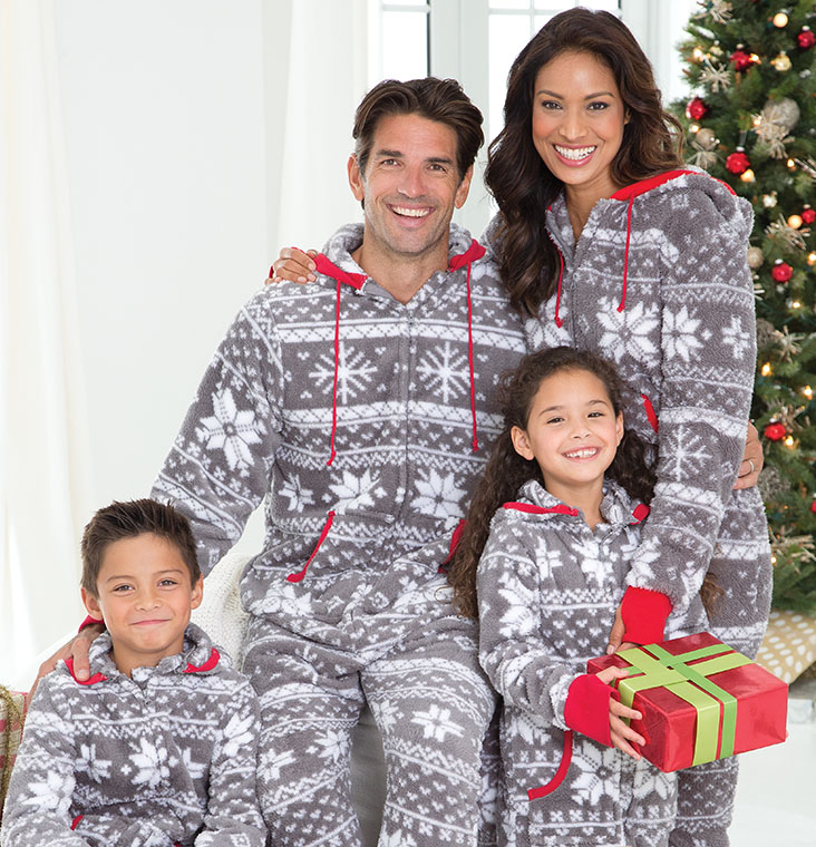 A family posing in front of a Christmas tree wearing PajamaGram Nordic Fleece Hoodie-Footie Matching Family Pajamas