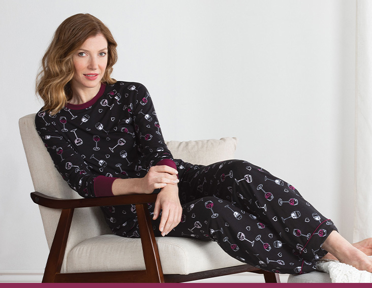 A model sitting back in a chair wearing PajamaGram Wine Down pajamas