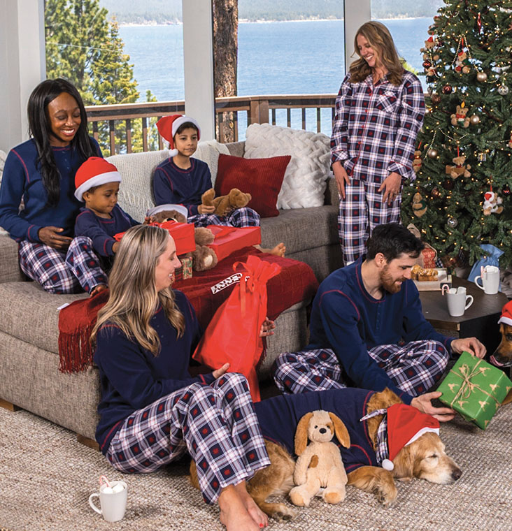 A family gathered around a Christmas tree wearing Pajamagram Snowfall Plaid Matching Family Pajamas