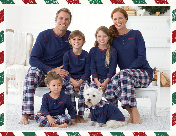 A family sitting together in their living room, laughing, wearing PajamaGram Snowfall Plaid Matching Family Pajamas