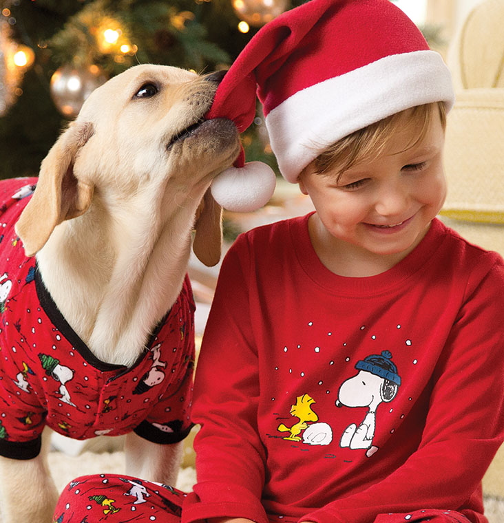 A young boy playing with his dog wearing PajamaGram Snoopy & Woodstock Matching Pet and Owner pajamas